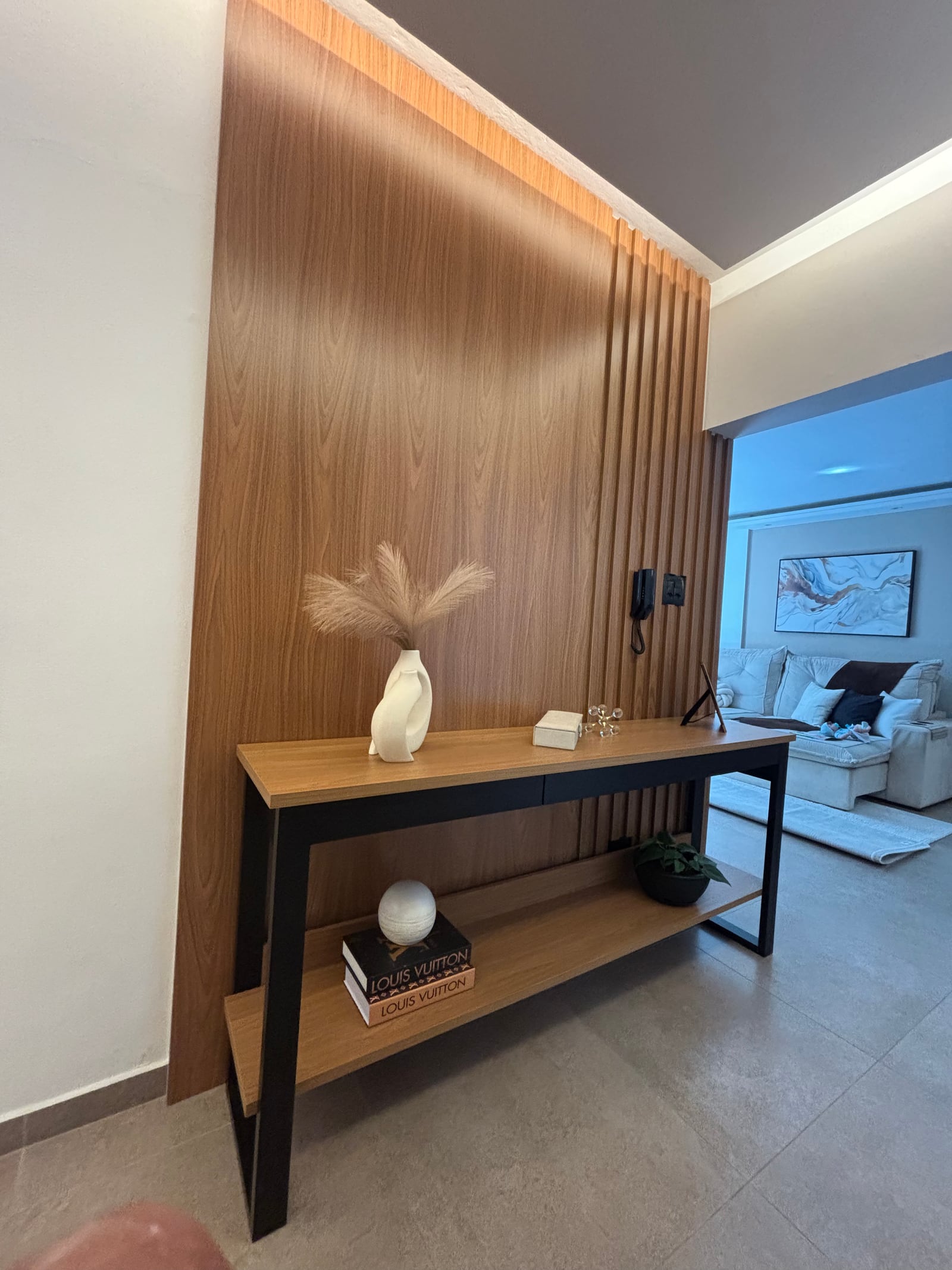 Aparador planejado em hall de entrada com painel ripado e iluminação embutida